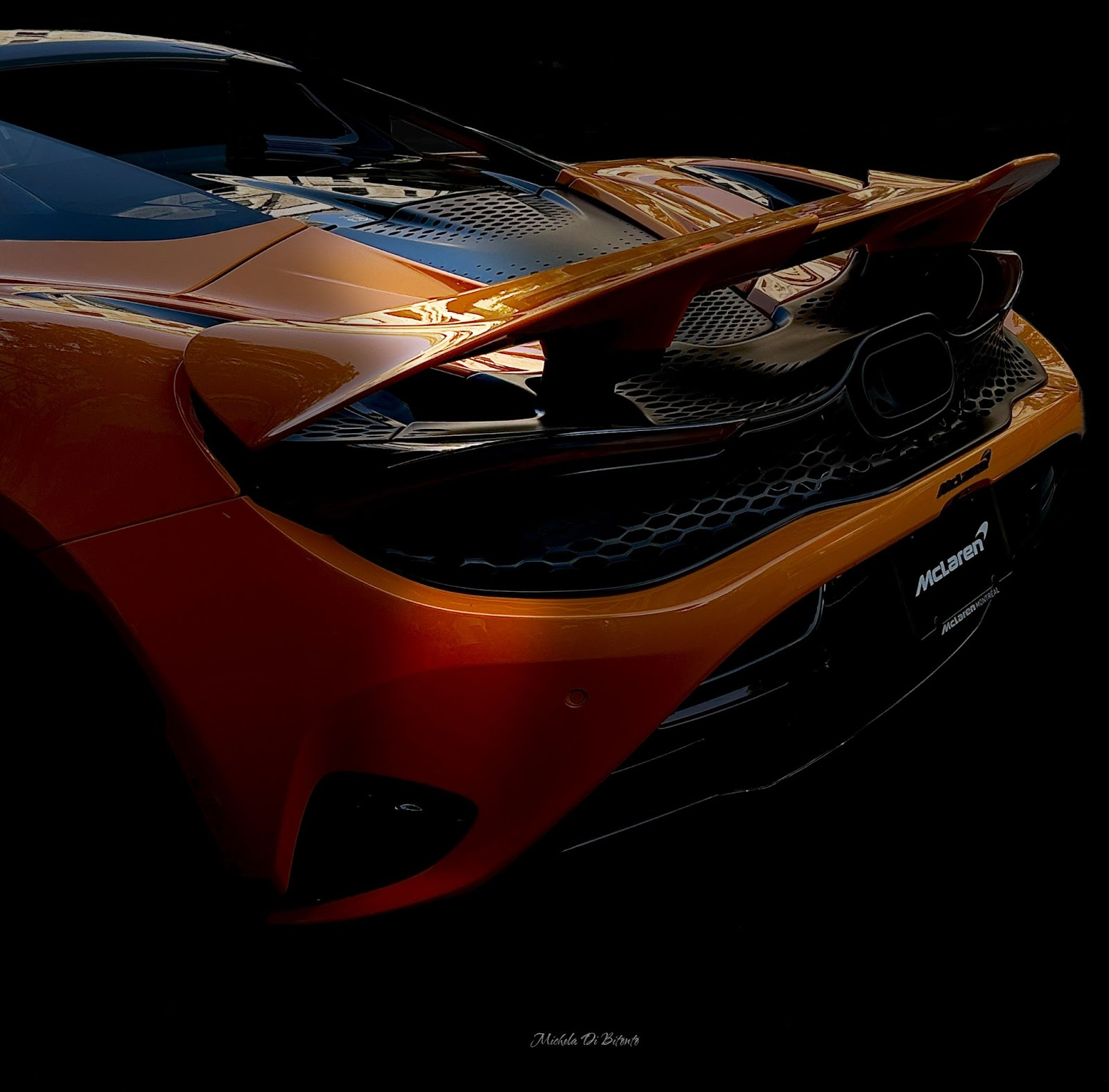 Picture of the rear of a McLaren spider, bright orange a the grand prix